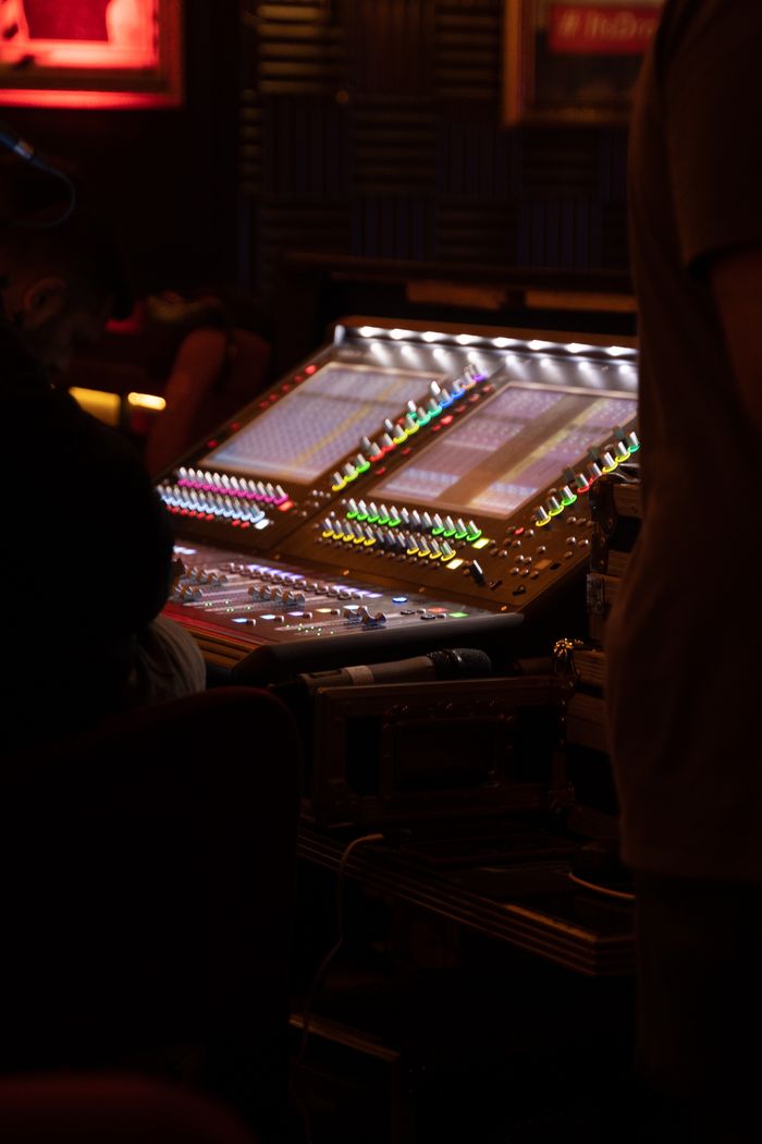services-01 A professional sound mixer with colorful lights and audio equipment in a dark recording studio.