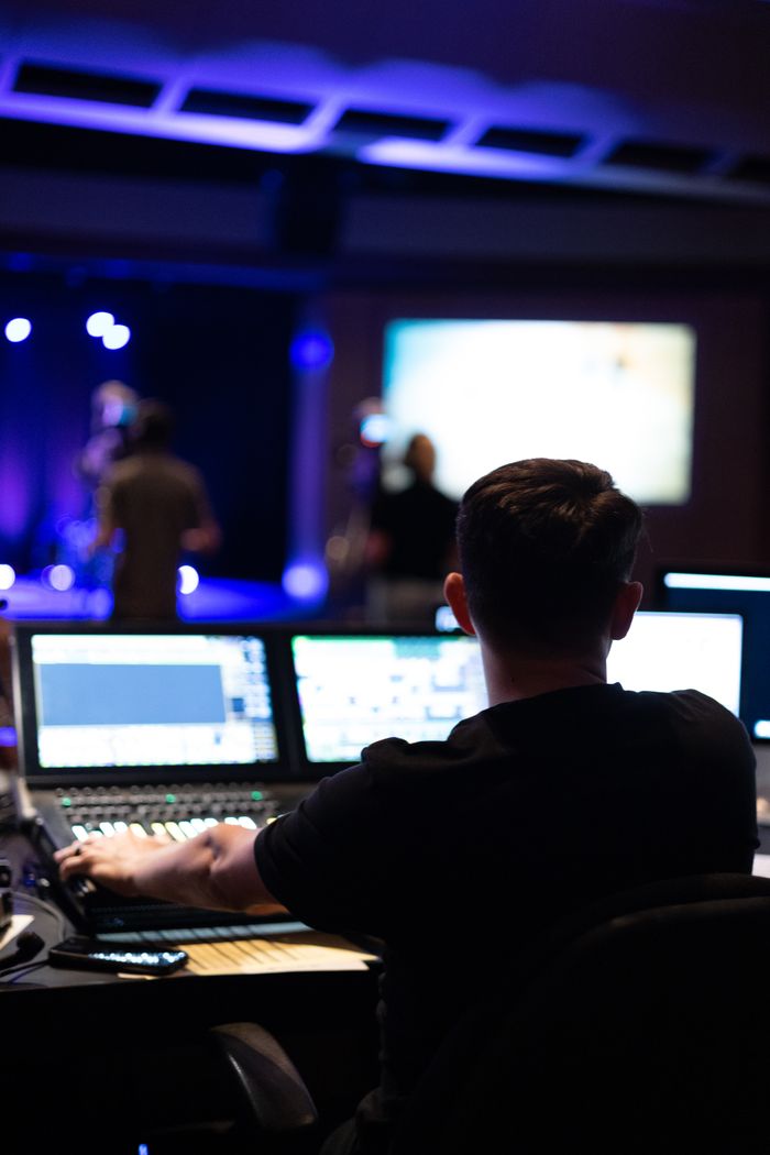 why-choose-us Sound engineer working at mixing console during a live studio performance.