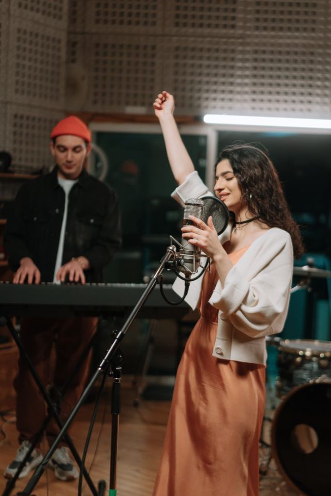 pexels photo 7090868 Energetic woman singing with keyboard accompaniment in a music studio.
